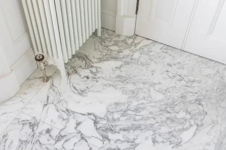 Veined white marble floor and wall panels in an en suite by Stonecraft