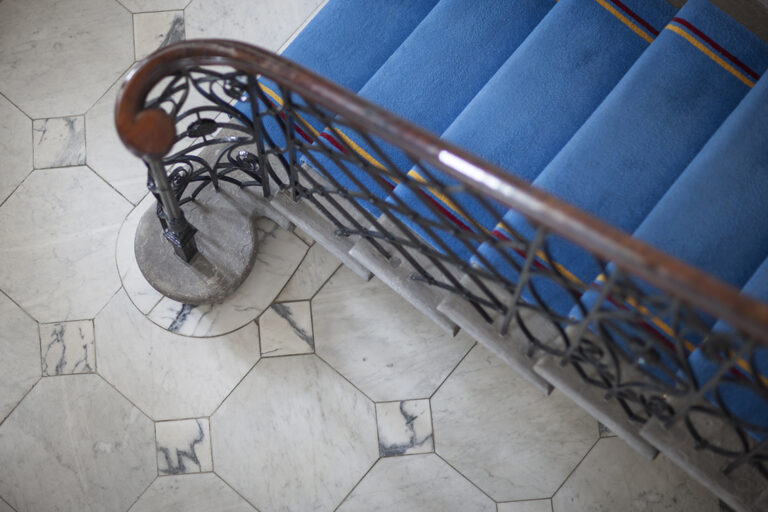 Octagonal marble floor tiles beside a wrought-iron staircase by Stonecraft